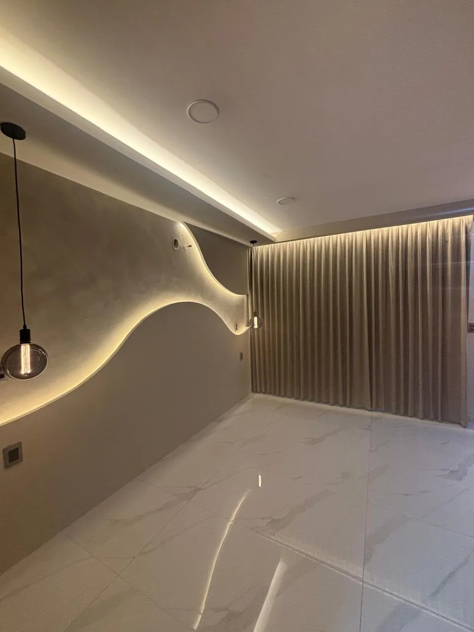 Muro texturizado con luz LED y cortinas de piso a techo en casa de Morelia