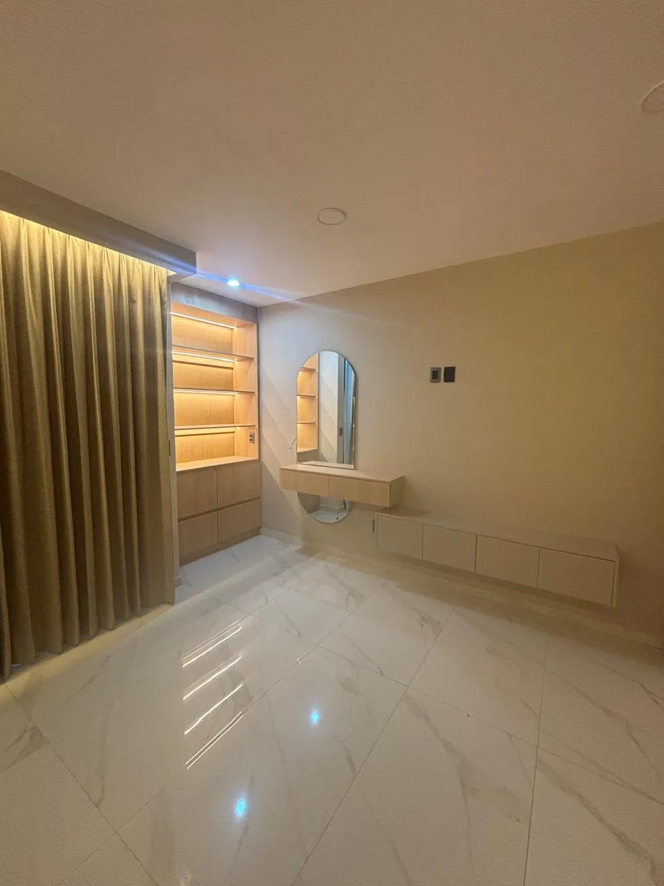 Vestidor a medida en madera clara con repisas iluminadas, espejo ovalado y tocador flotante en Morelia